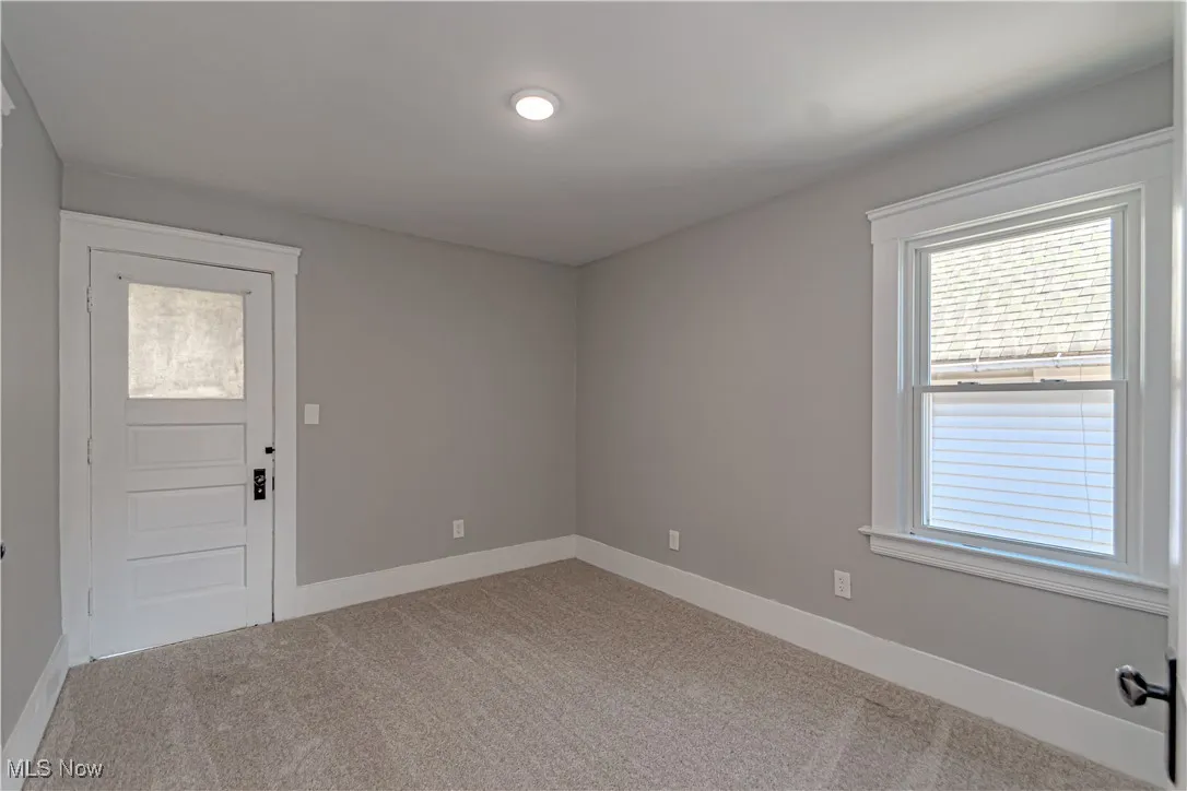 Empty room featuring baseboards and light carpet