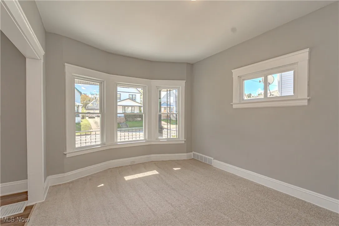 Empty room featuring baseboards and light carpet