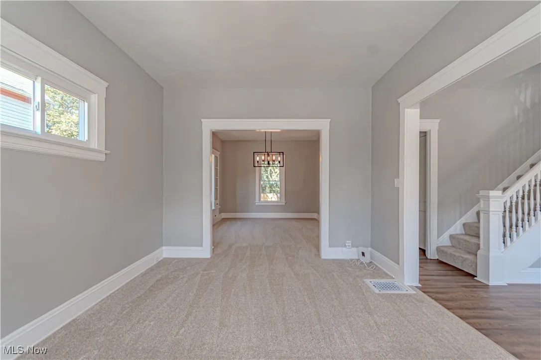 Spare room featuring stairs, carpet floors, and a chandelier