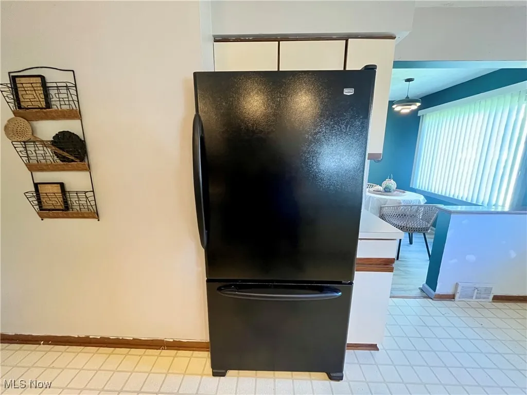 Kitchen featuring freestanding refrigerator, white cabinetry, light countertops, and light tile patterned floors