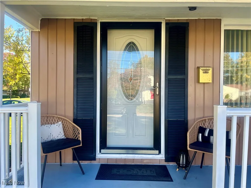 View of exterior entry with board and batten siding and a porch