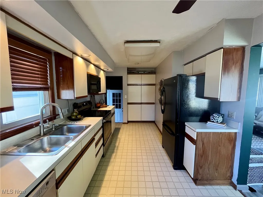 Kitchen with black appliances, light countertops, and a ceiling fan