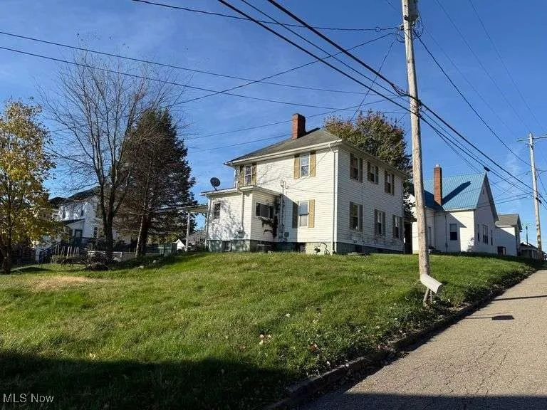 View of front facade featuring a front lawn and a chimney
