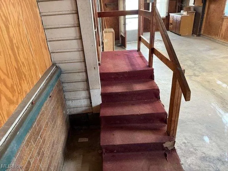 Staircase featuring wood walls