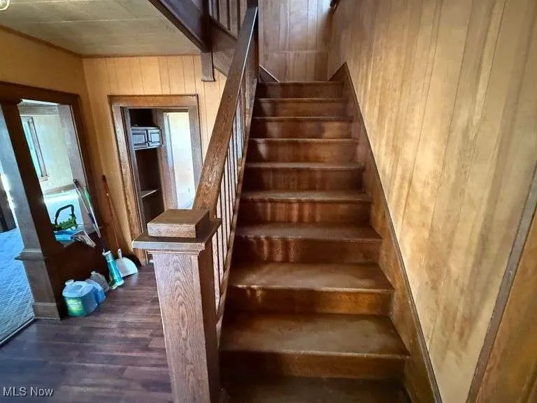 Staircase featuring wood finished floors and wood walls