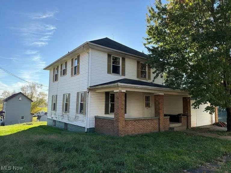 View of home's exterior featuring a lawn, a garage, a porch, and brick siding