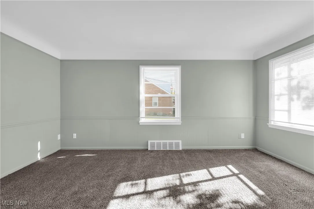 Carpeted empty room featuring wainscoting and baseboards