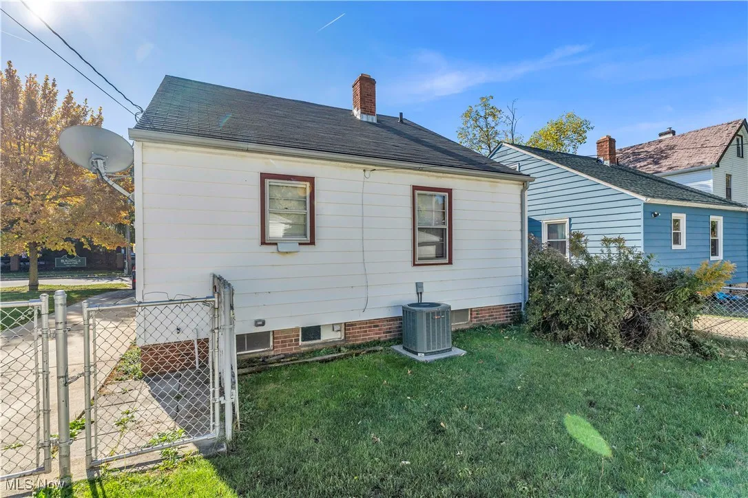View of side of home featuring a gate, a chimney, and roof with shingles