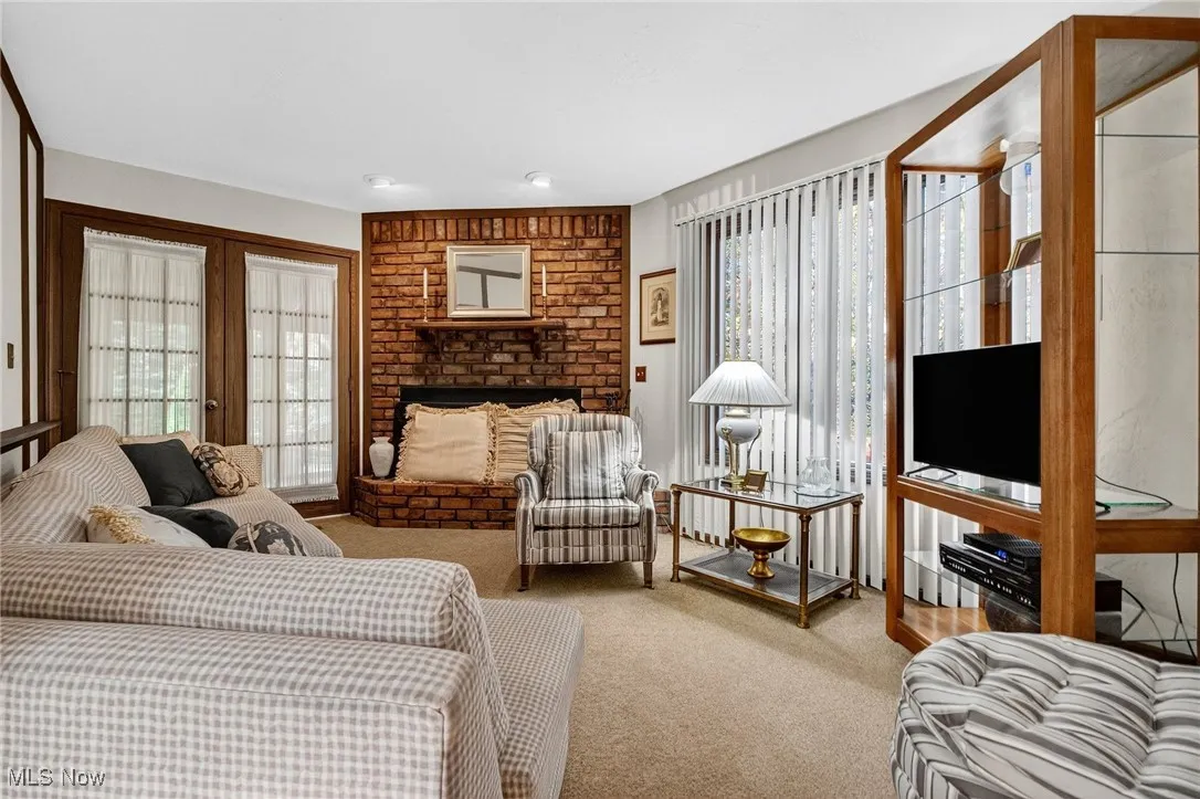Living area with a brick fireplace and carpet