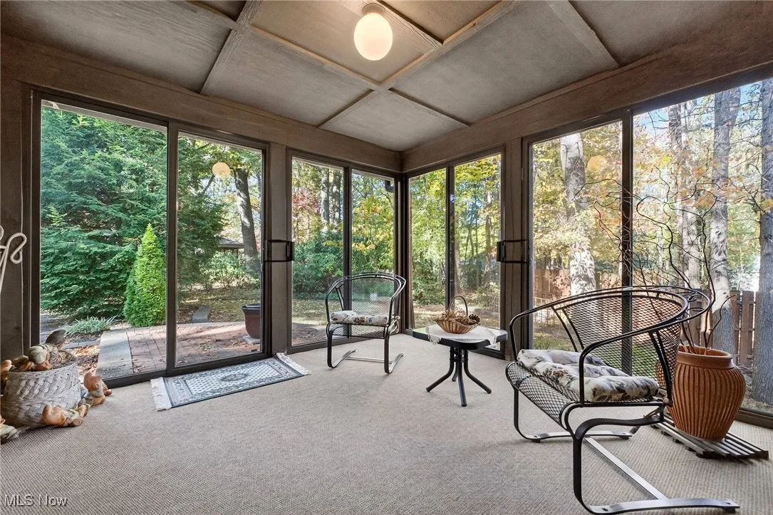 Sunroom with healthy amount of natural light, coffered ceiling, and view of scattered trees