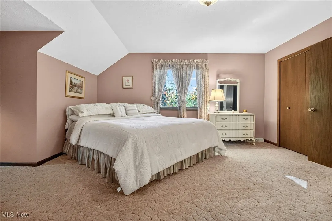 Bedroom with carpet floors, a closet, and lofted ceiling