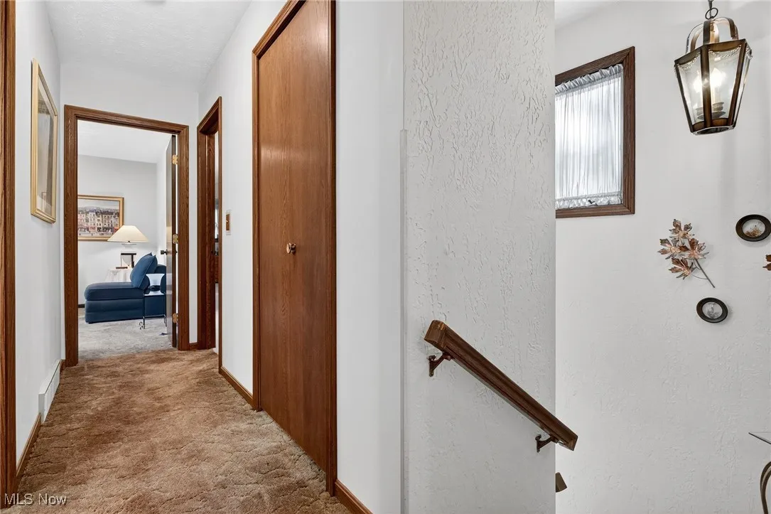 Hallway with light colored carpet and baseboards