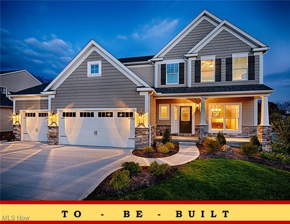 View of front of home with stone siding, a porch, concrete driveway, and a yard