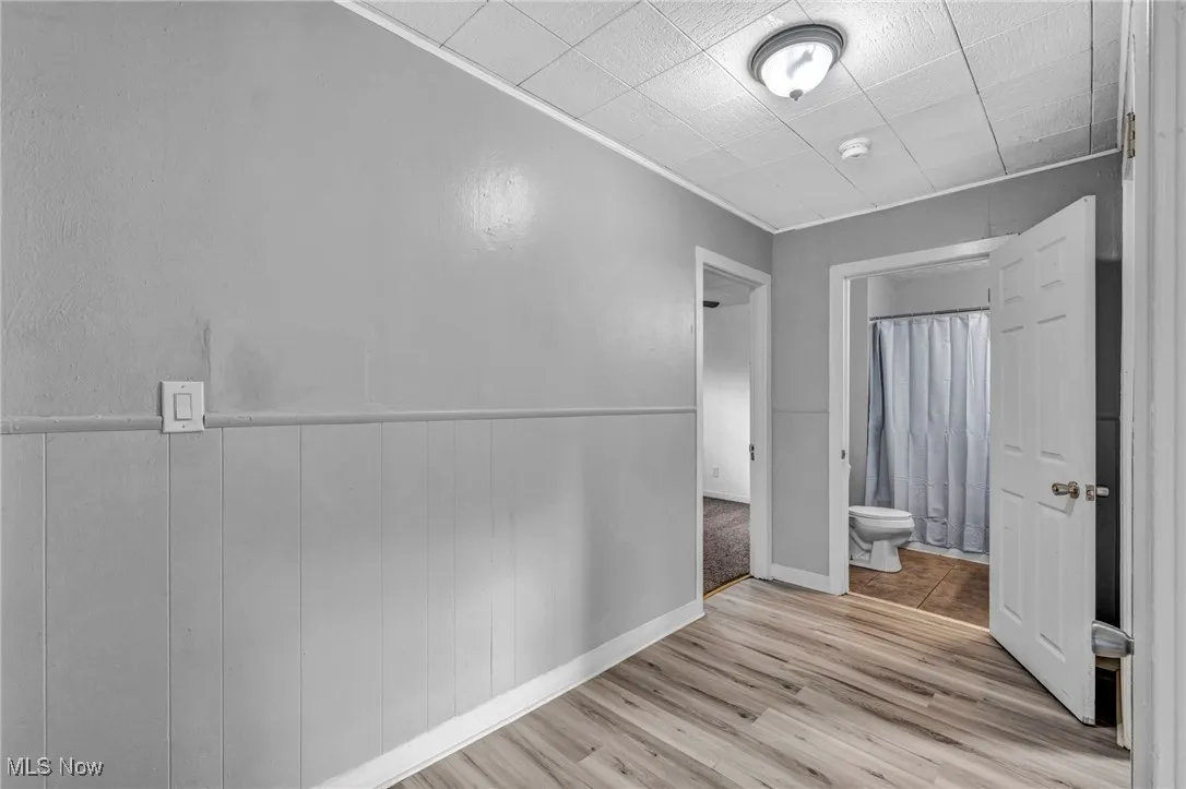 Hallway featuring light wood finished floors and a wainscoted wall