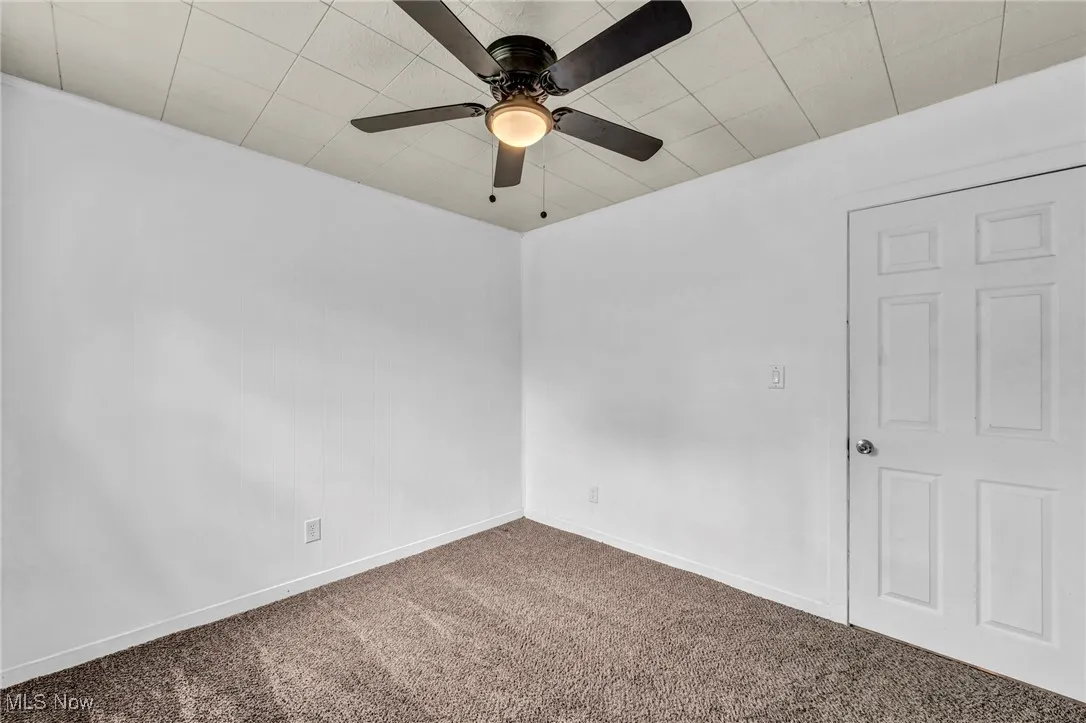 Carpeted spare room featuring baseboards and a ceiling fan