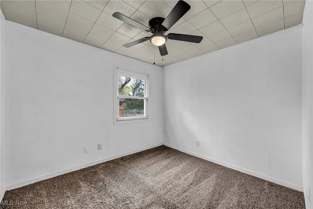Carpeted spare room featuring baseboards and a ceiling fan