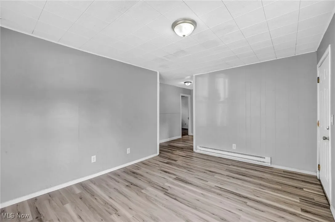 Unfurnished room featuring baseboard heating and light wood finished floors