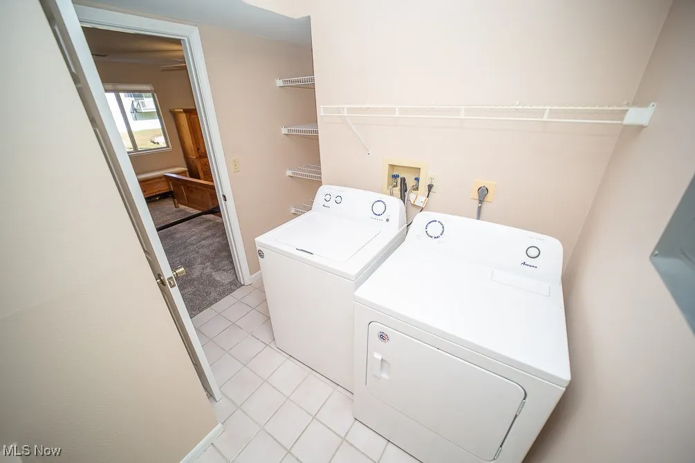 Washroom featuring light tile patterned floors, separate washer and dryer, and light colored carpet