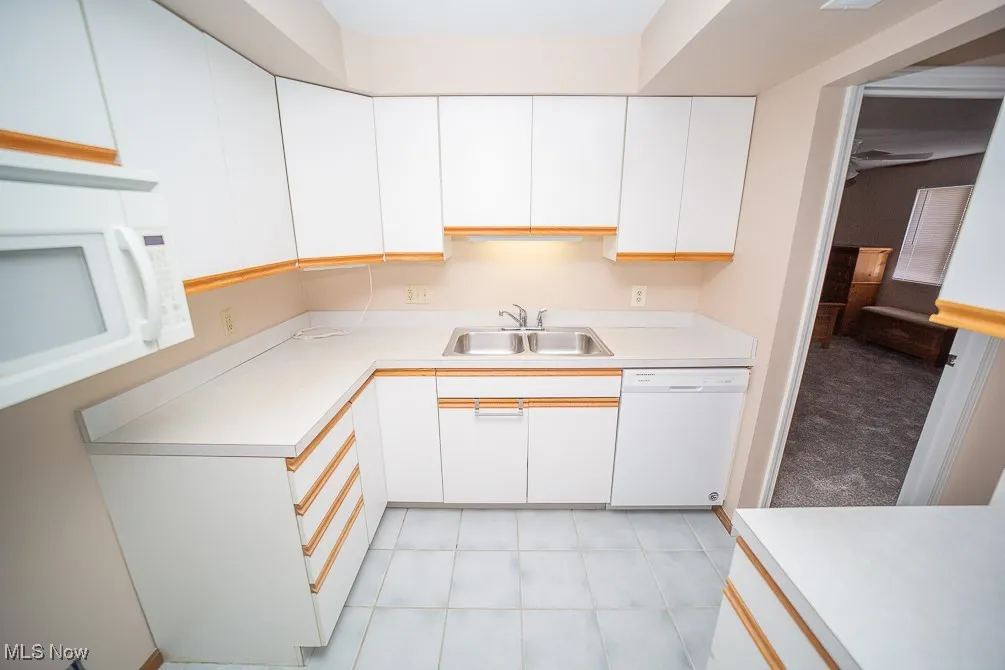 Kitchen featuring white cabinets, light countertops, white appliances, and light tile patterned floors