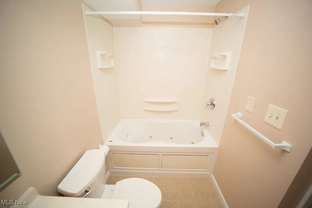 Bathroom with a combined bath / shower with jetted tub and light tile patterned flooring