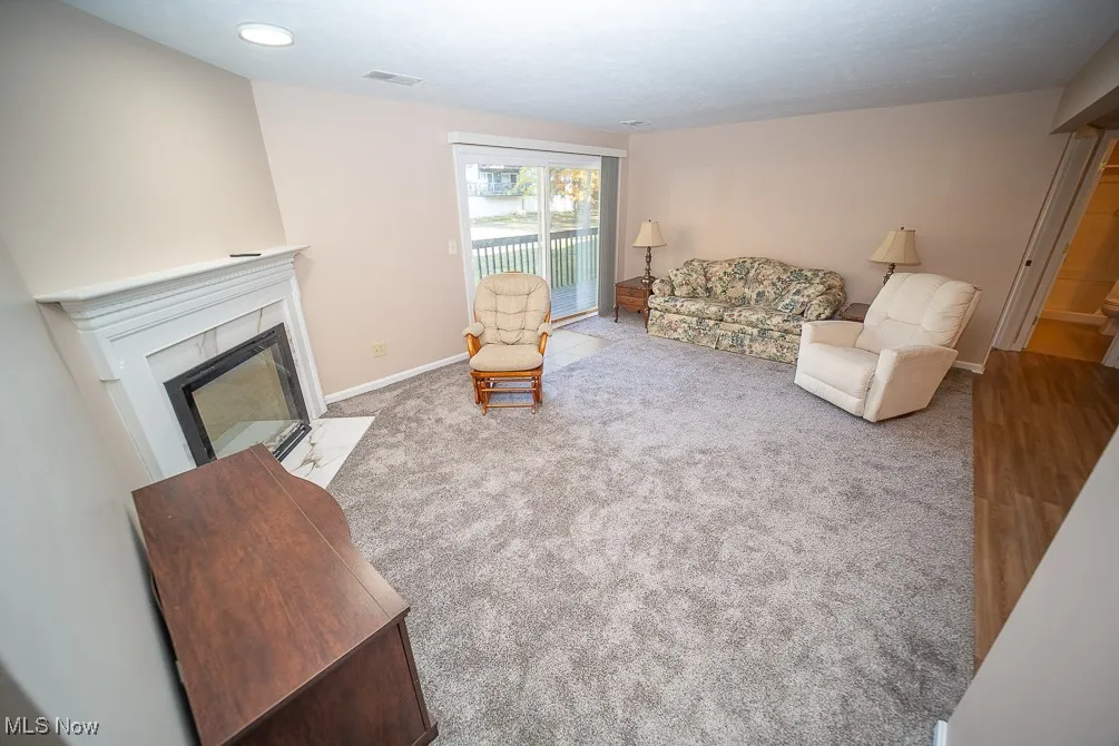 Carpeted living room featuring a tiled fireplace and baseboards