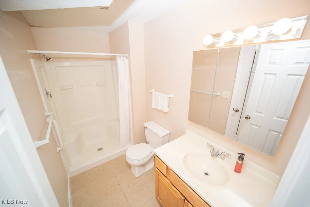 Full bathroom featuring a stall shower, light tile patterned floors, and vanity