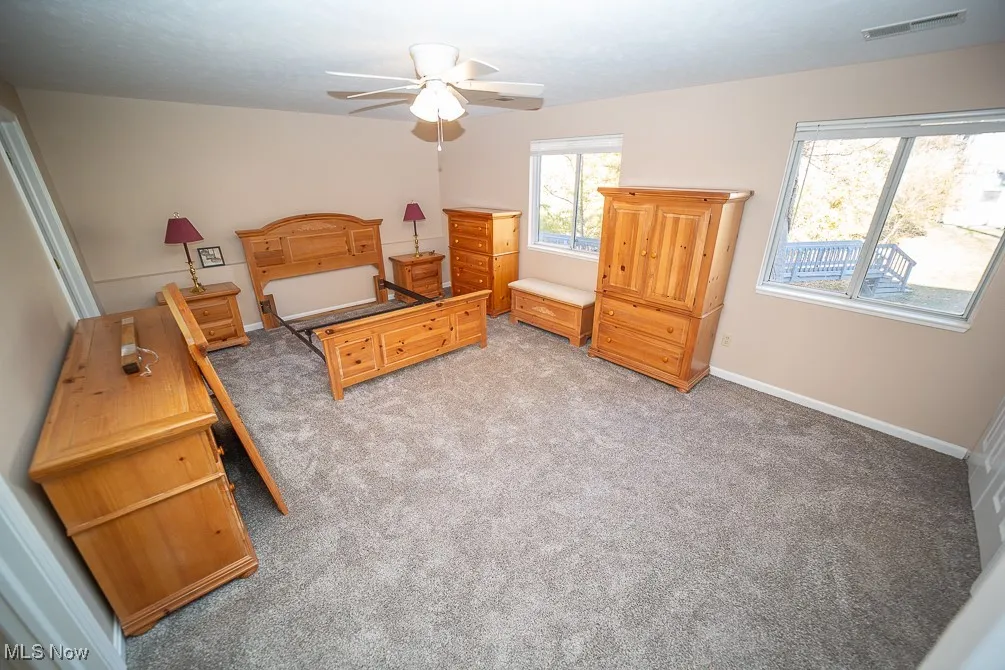 Bedroom with light colored carpet and a ceiling fan
