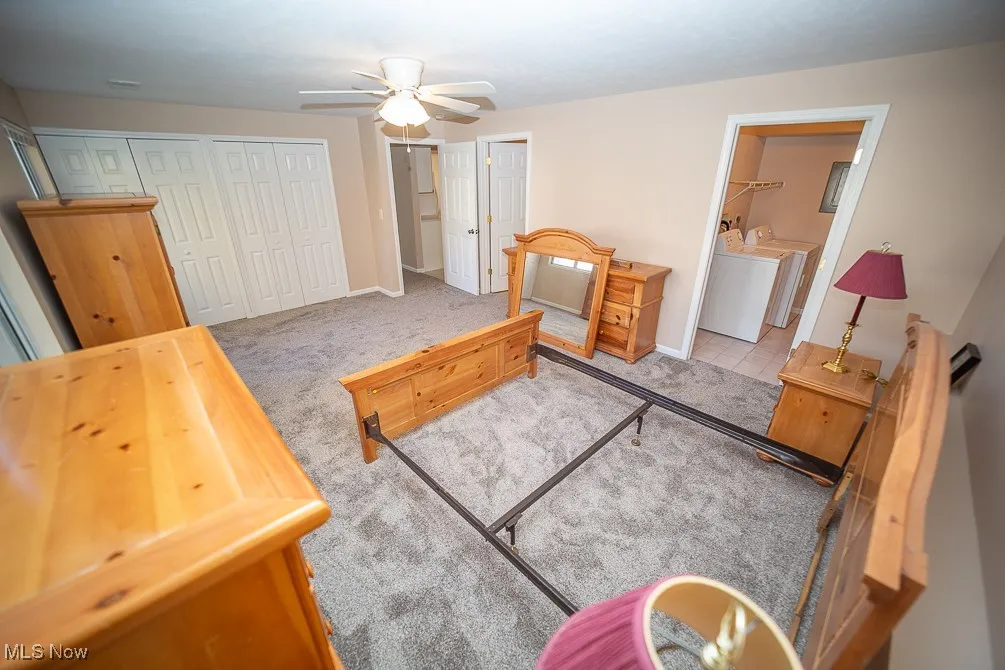 Bedroom with two closets, washer and clothes dryer, carpet, and a ceiling fan