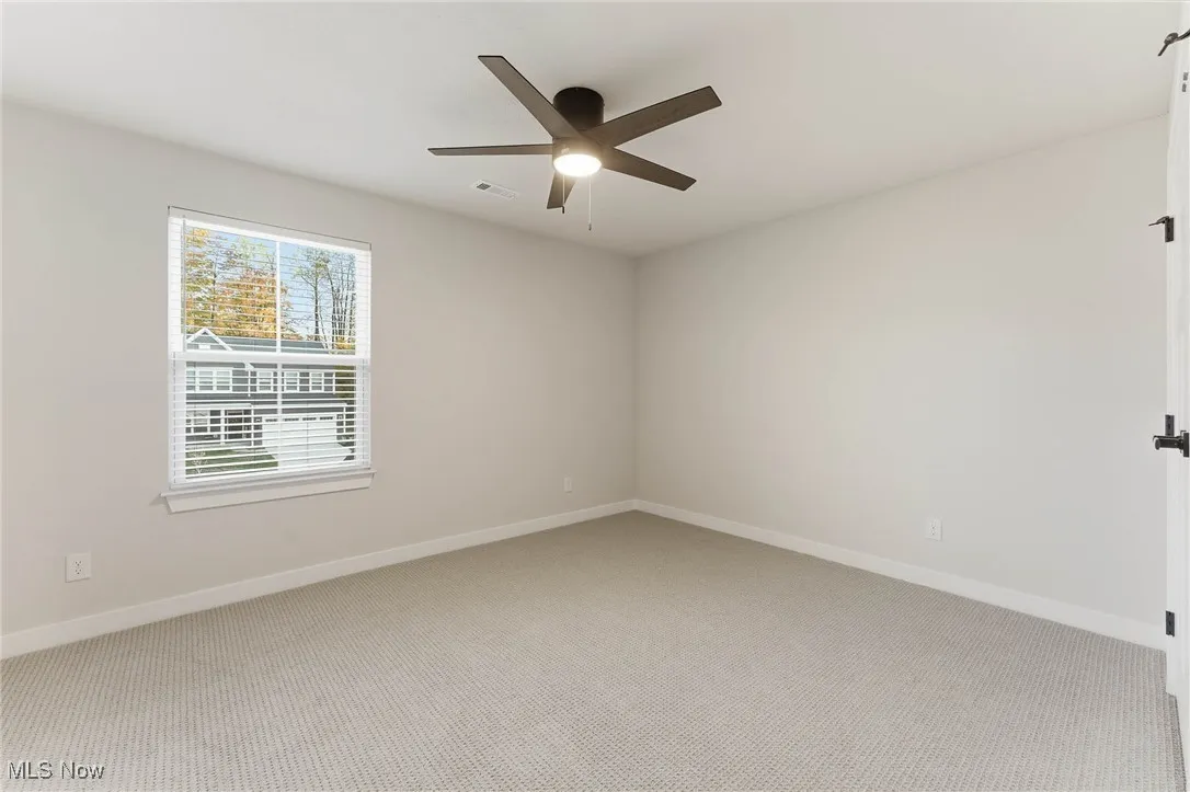 Carpeted empty room featuring baseboards and ceiling fan