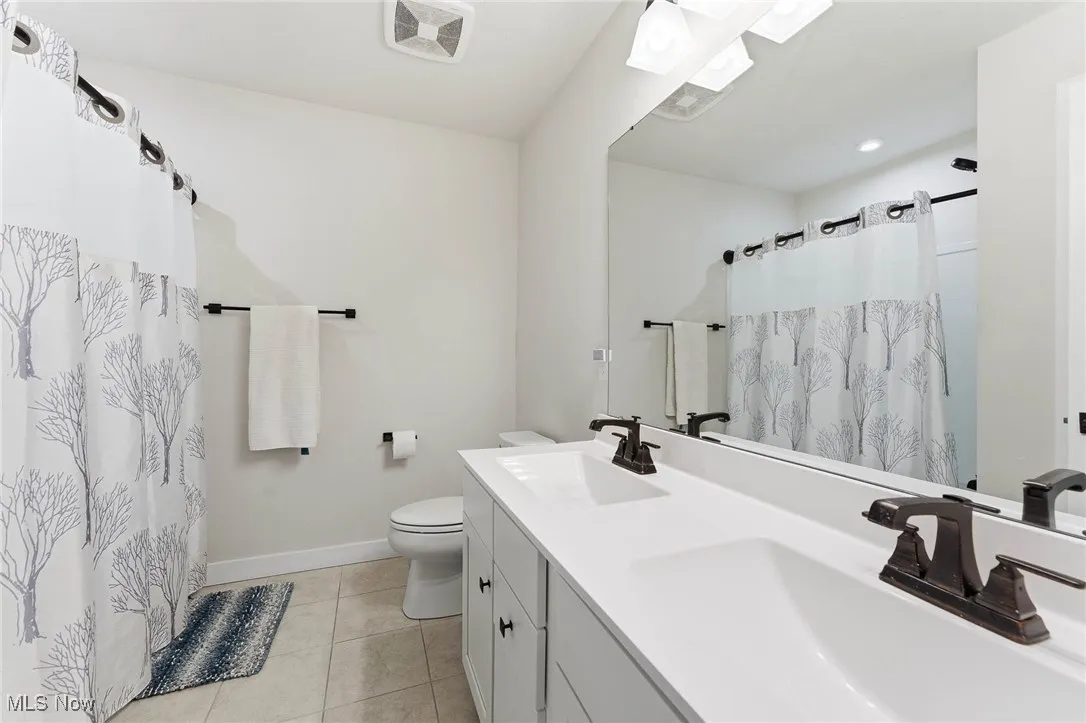 Full bathroom with double vanity, light tile patterned floors, a shower with curtain, and recessed lighting