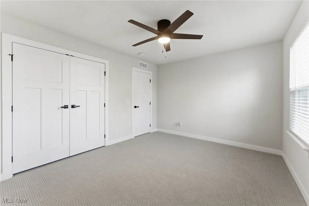 Unfurnished bedroom featuring carpet flooring, a closet, and a ceiling fan