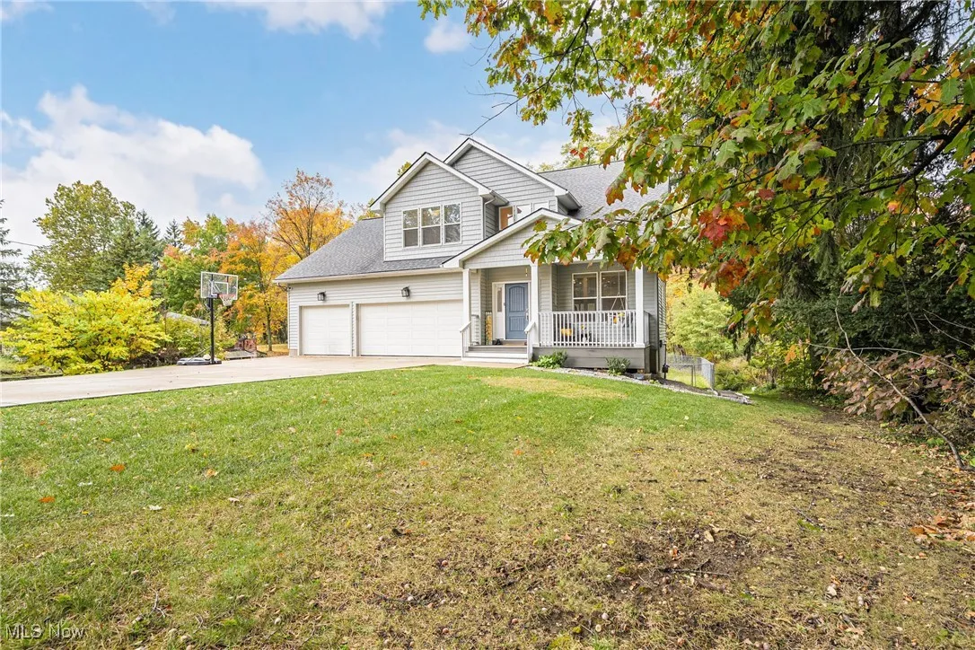 Traditional-style home featuring a porch, driveway, a front yard, a garage, and a shingled roof