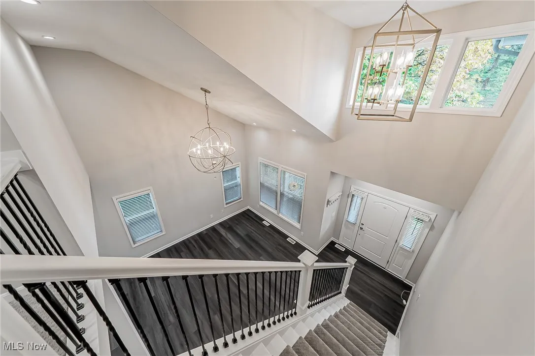 Entrance foyer featuring a chandelier, healthy amount of natural light, a high ceiling, Luxury vinyl tile wood-style finished floors, and stairway