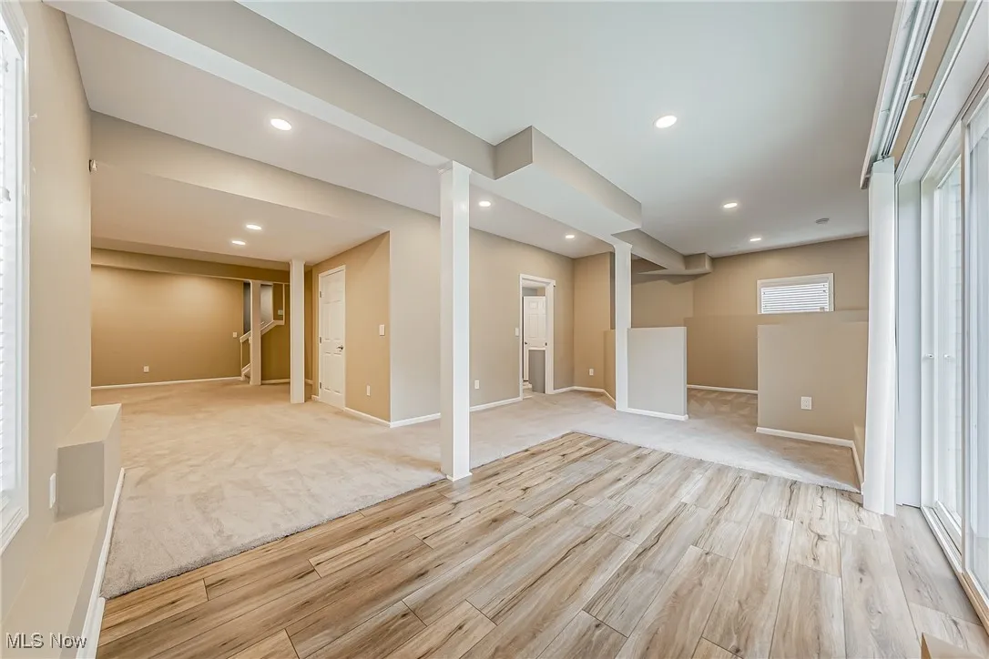 Walk-out basement with light wood-style floors, recessed lighting, and light colored carpet