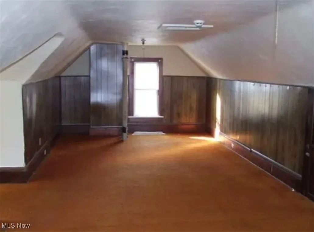Bonus room with wooden walls, lofted ceiling, and carpet flooring