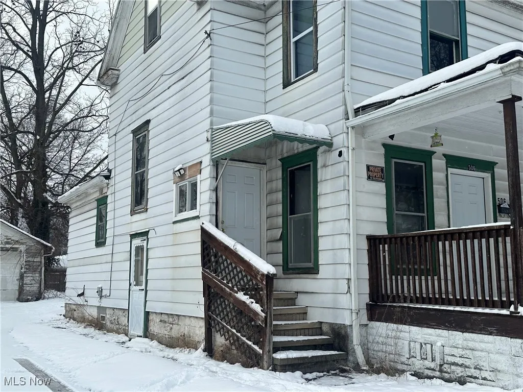 Snow covered property entrance featuring covered porch