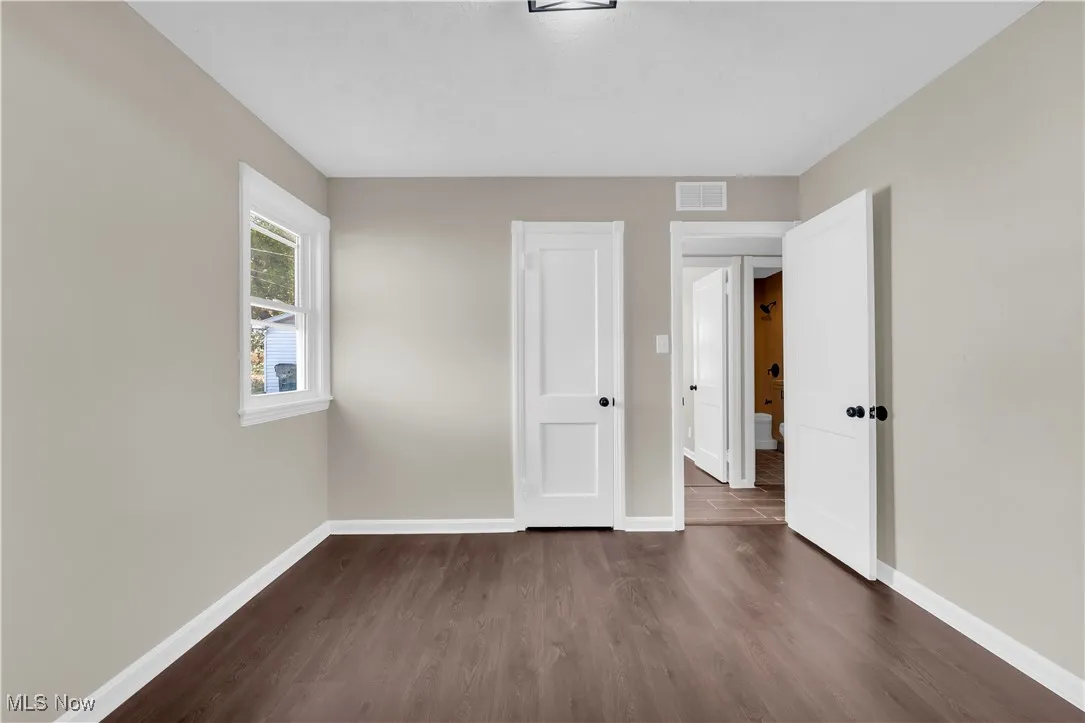 Unfurnished bedroom featuring dark wood-style floors and a closet