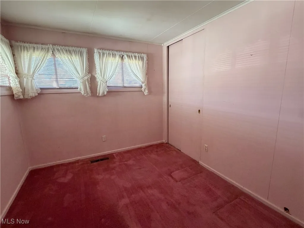 Unfurnished bedroom featuring dark colored carpet and a closet