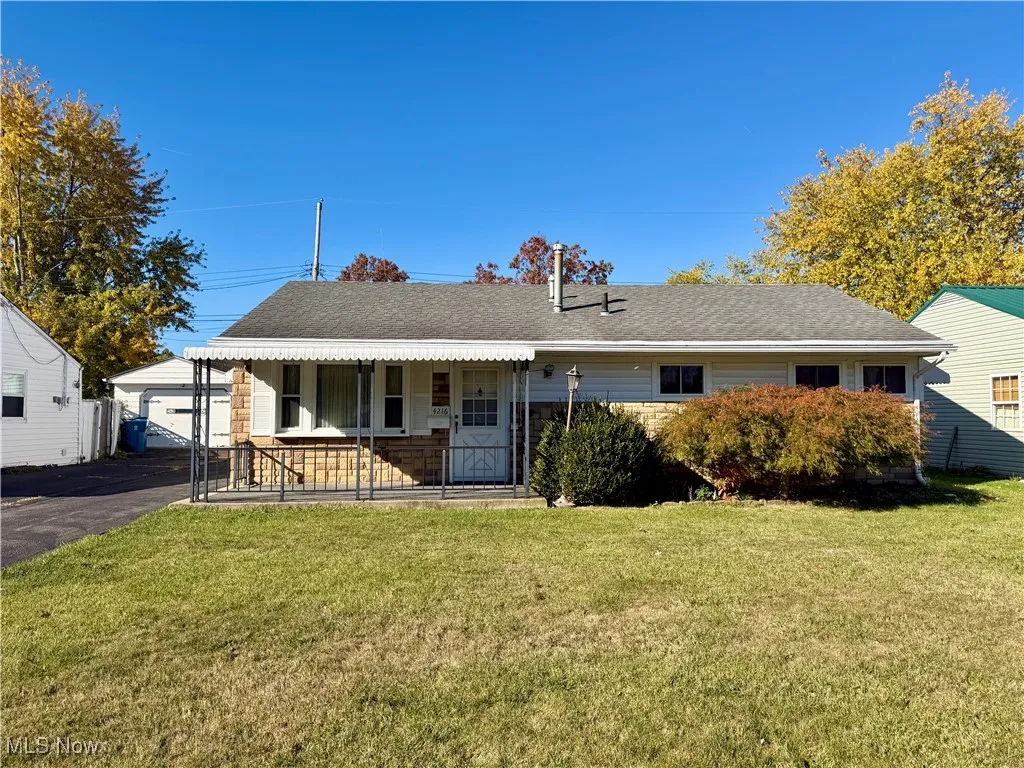 Ranch-style house with a shingled roof, a front lawn, and a porch