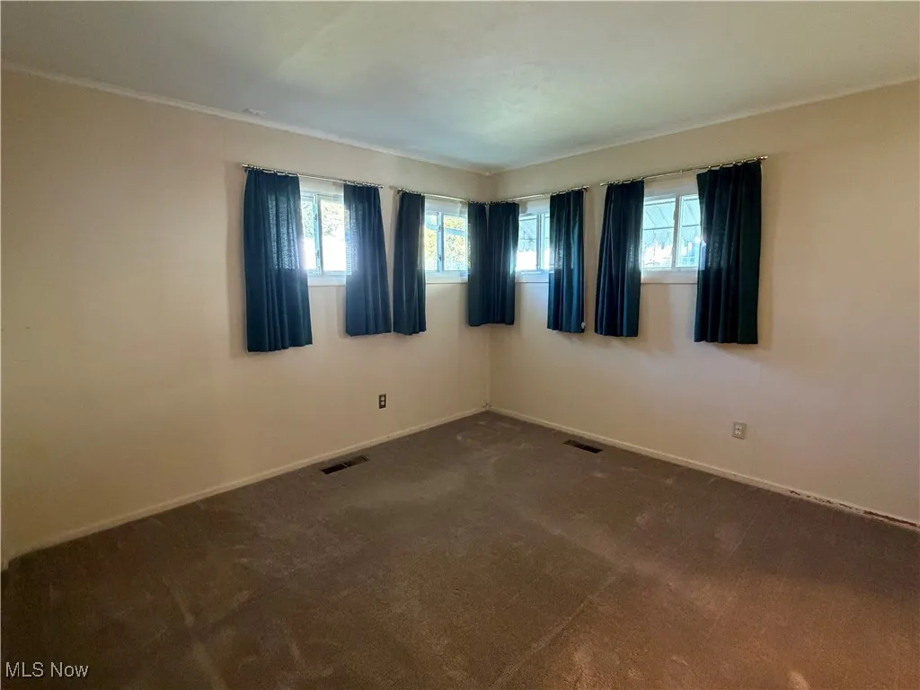 Spare room with healthy amount of natural light and dark colored carpet