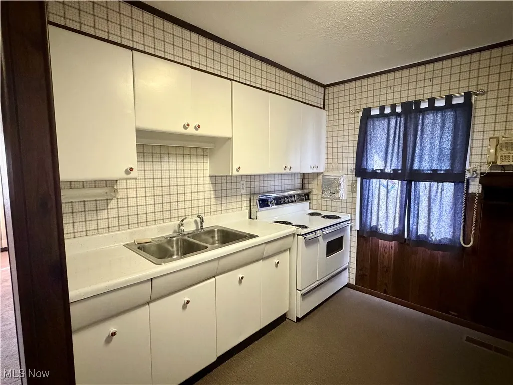 Kitchen with range with two ovens, a textured ceiling, light countertops, decorative backsplash, and white cabinetry