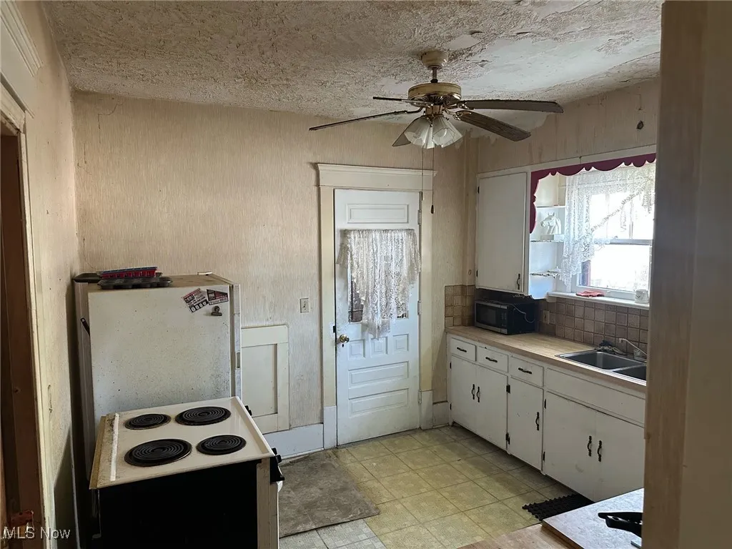 Kitchen with white cabinetry, ceiling fan, electric range oven, a textured ceiling, and stainless steel microwave