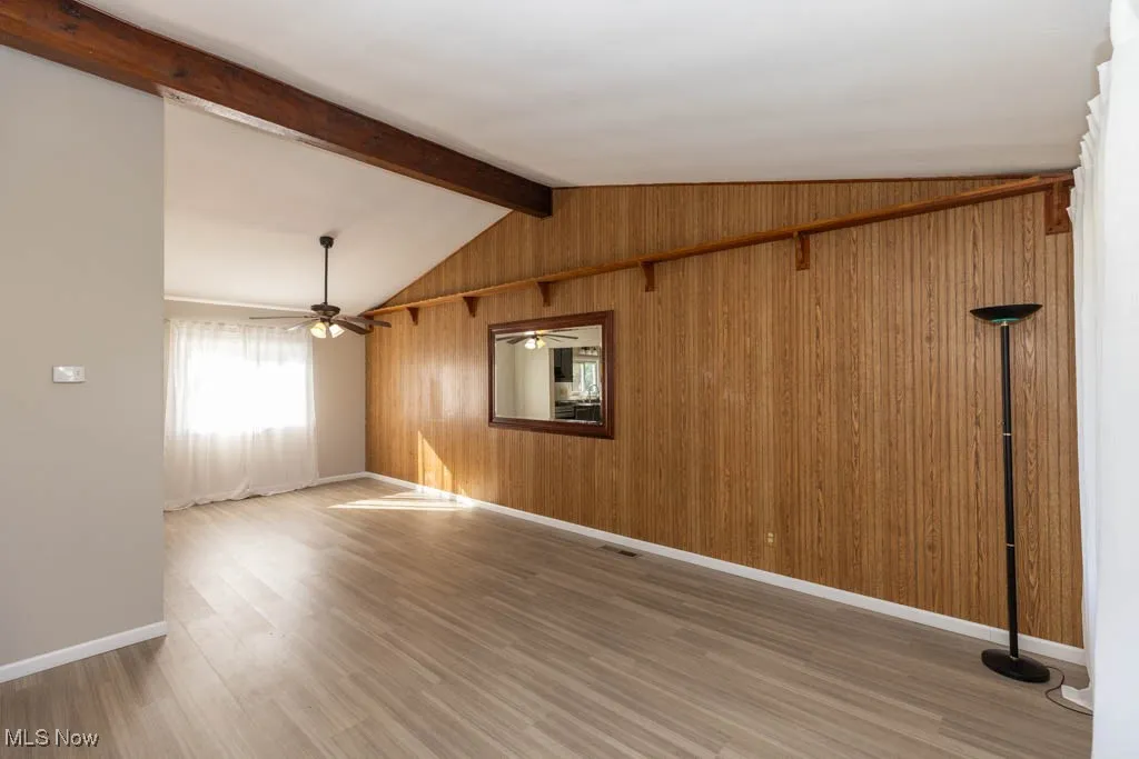 Unfurnished room featuring light wood-style flooring and wood​​‌​​​​‌​​‌‌​‌‌​​​‌‌​‌​‌​‌​​​‌​​ walls