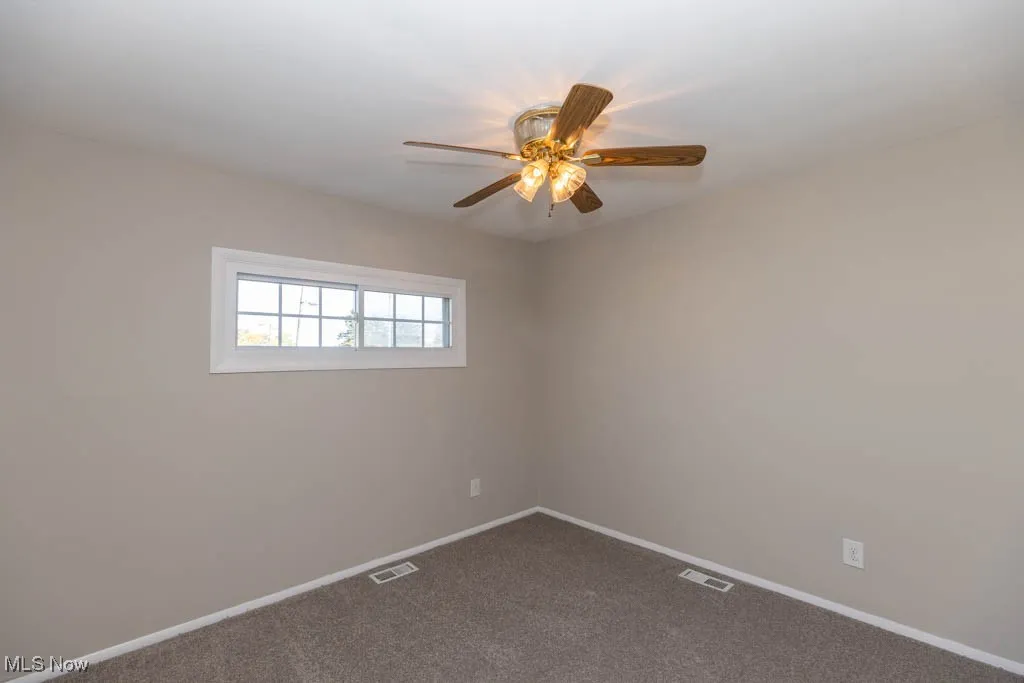 Carpeted empty room featuring baseboards and ceiling fan