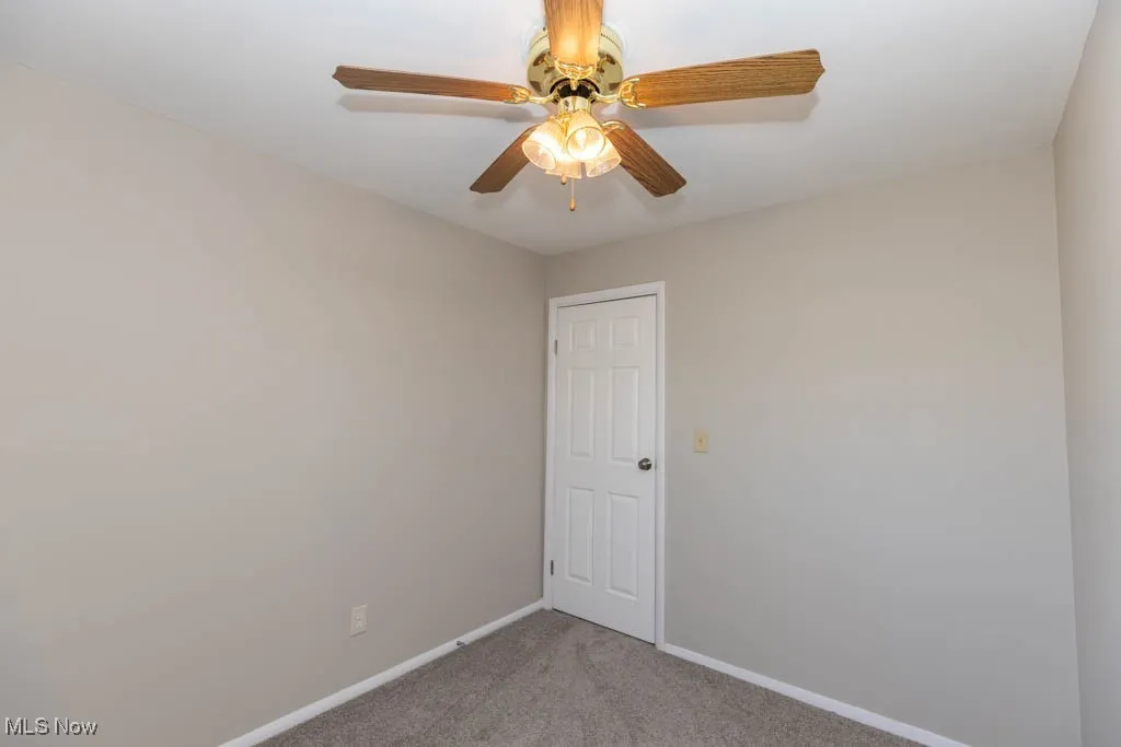 Spare room featuring light carpet and ceiling fan