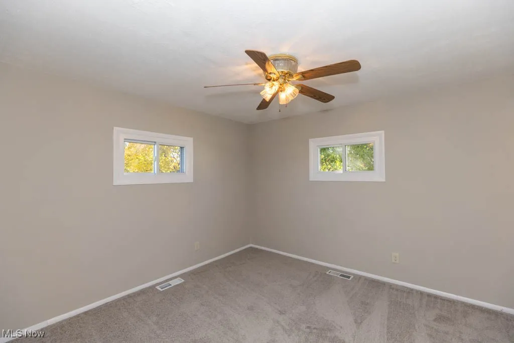 Unfurnished room with light colored carpet and a ceiling fan