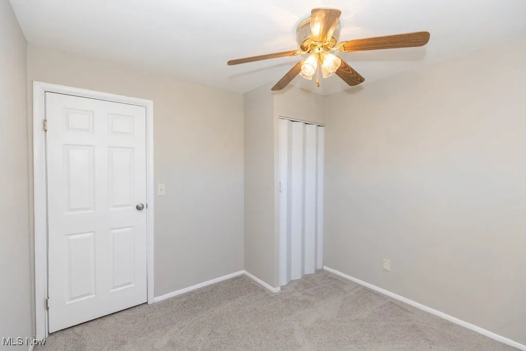 Unfurnished bedroom featuring light colored carpet, ceiling fan, and a closet