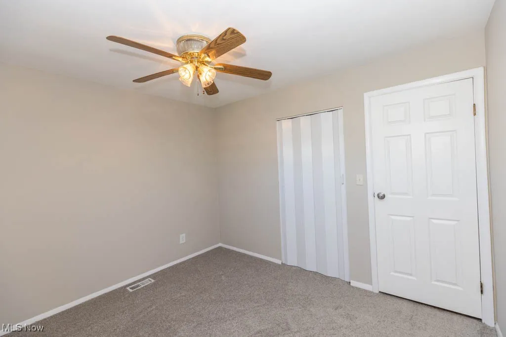 Unfurnished bedroom featuring light carpet and ceiling fan