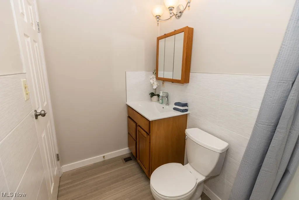 Bathroom with vanity, tile walls, and light wood finished floors