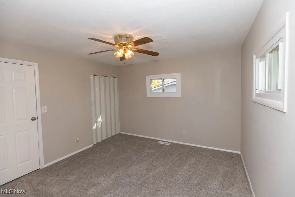 Carpeted empty room with baseboards and ceiling fan
